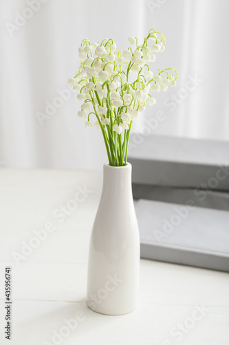Vase with beautiful lily-of-the-valley flowers on table