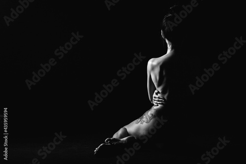 silhouette of a young, slender, on a black background in a photo studio