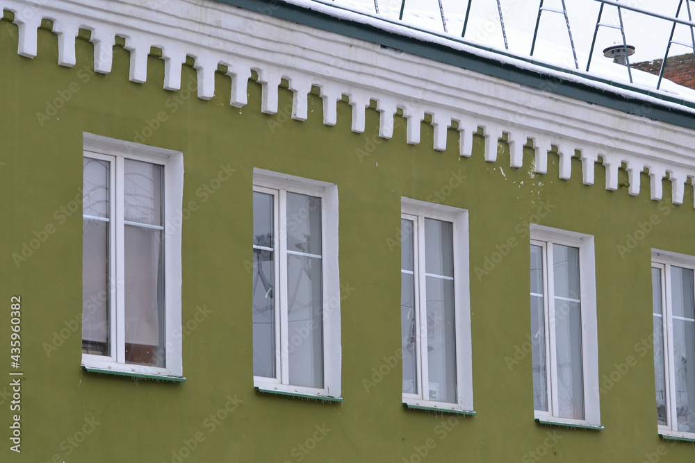  Elements of the architectural decor of the building. A fragment of the facade of a restored old house with color walls and white window frames.
