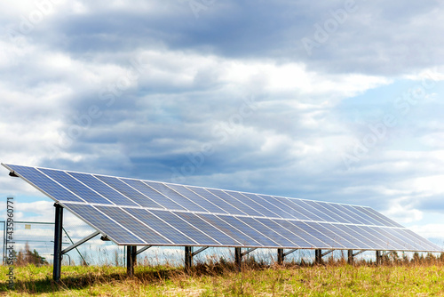 Solar panels in a field.line of solar electric generation panels on rural meadow.Cloudy evening sky background.