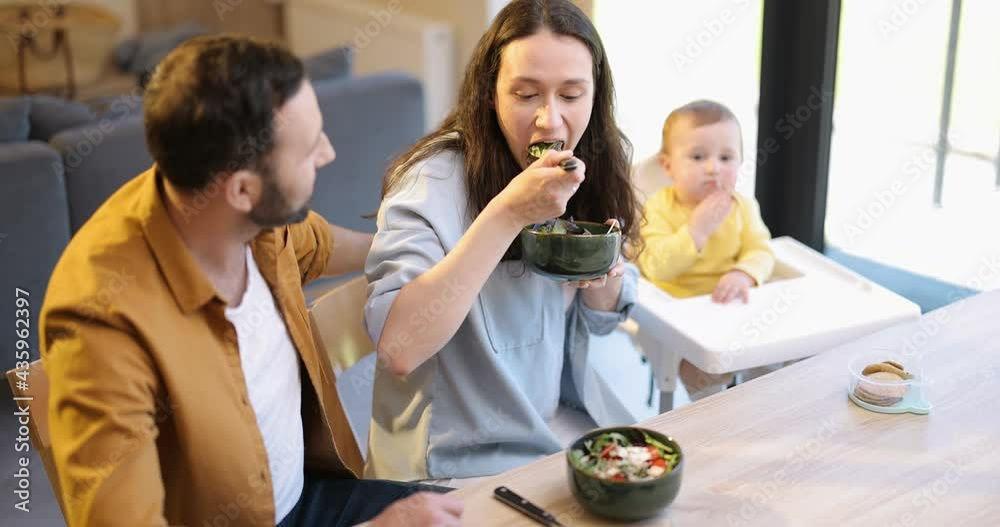 Young happy family with a one year baby boy during a lunch time at home. Concept of healthy vegan eating and happy parenting Young happy family with a one year baby boy during a lunch time at home. Concept of healthy vegan eating and happy parenting