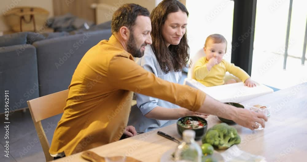 Young happy family with a one year baby boy during a lunch time at home. Concept of healthy vegan eating and happy parenting