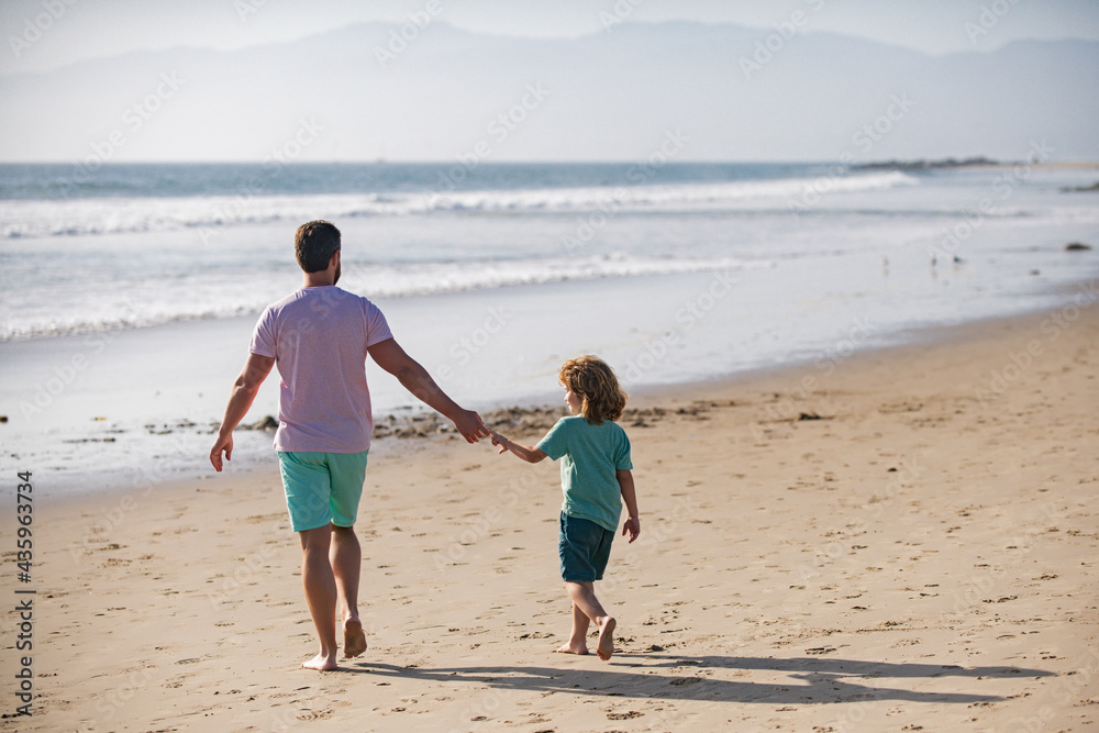 Father and son walking on sea. Dad and child having fun outdoors.
