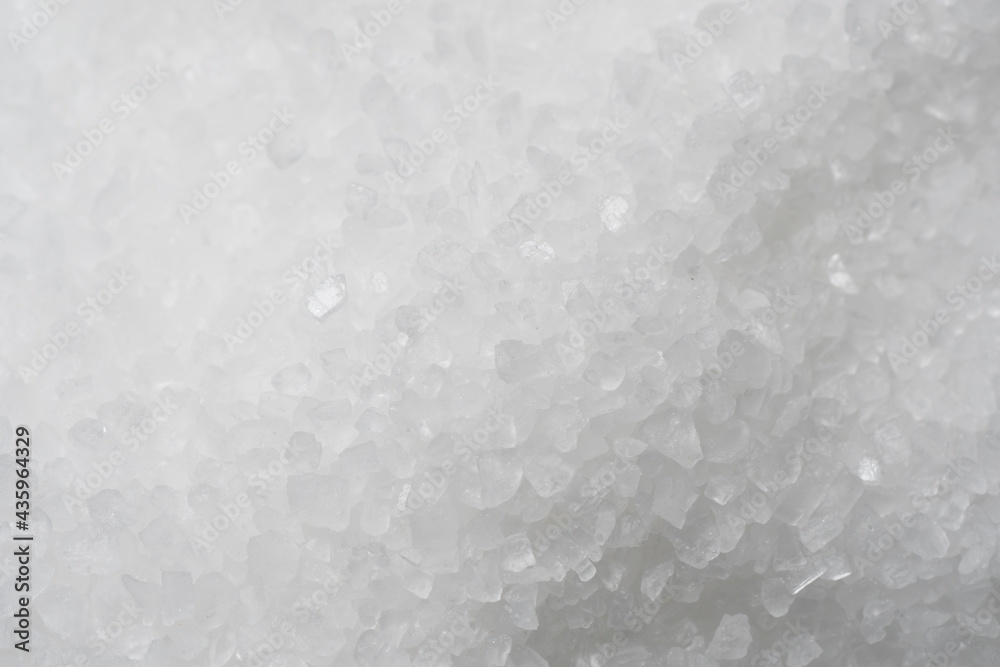Textured background, top view of a pile of grains of white sea salt.