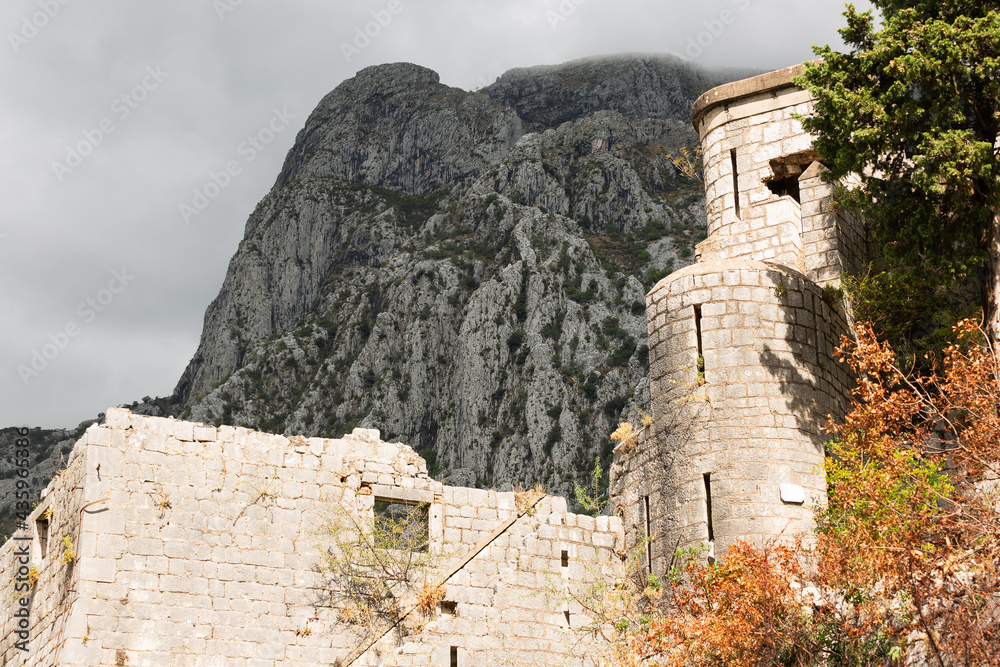 Wall of the old fortress against the background of the black mountain. Kotor, Montenegro
