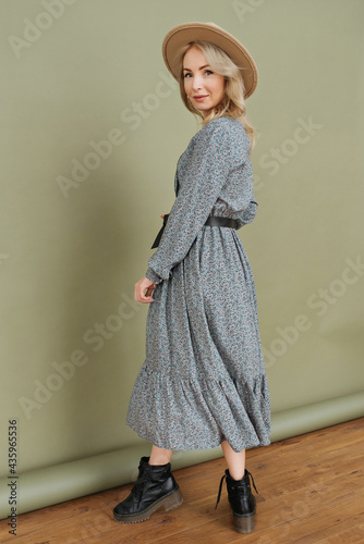 Luxurious young slim girl with long hair in a long dress with a floral print and a straw hat. Getting ready is going on a date on a warm summer evening