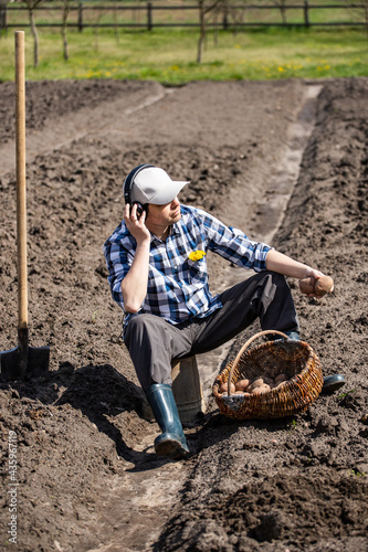 person planting potatoes in the field and listens to music