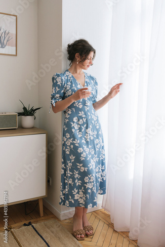 adult young woman is resting in a beautiful feminine blue dress in a bright room by the window relax rest break anticipation anticipation date