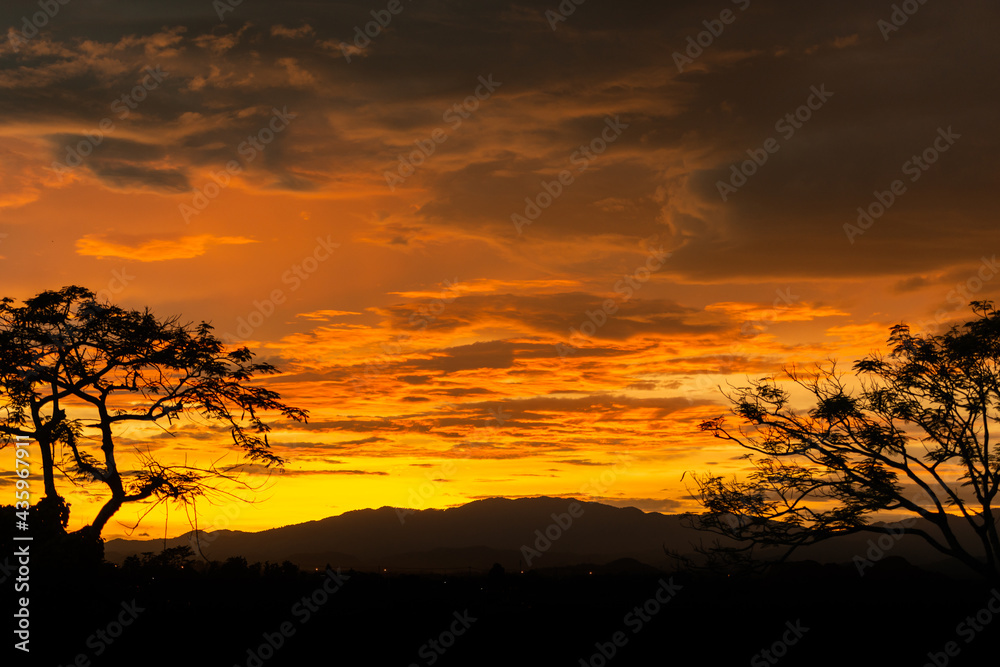 Sunset behind a mountain with a tree facing Sunset behind a mountain with a tree facing