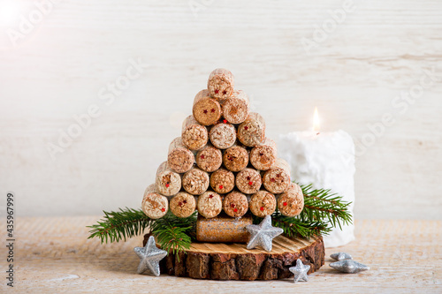 Handmade creative Christmas tree decoration made with wine bottle corks. White candle burning on wooden background  lot of copy space. Upcycling concept.