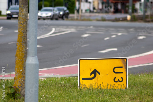 Yellow traffic sign for redirection on urban streets forces navigation system to calculate a new route for correct routing to reach your destination on German roads lying on grass after heavy storm photo