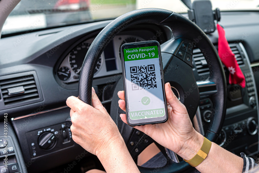 driver in car shows a digital coronavirus immunity vaccine passport, new normal travel concept driver in car shows a digital coronavirus immunity vaccine passport, new normal travel concept