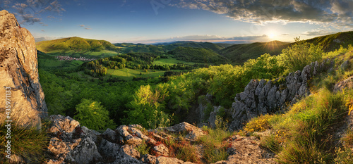 Green spring mountain landscape with sun and rocks - panorama