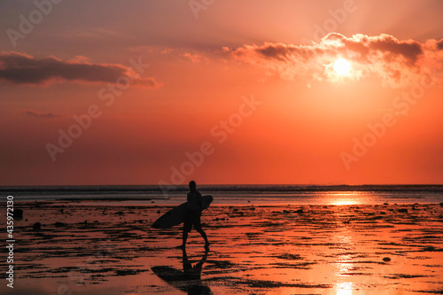Beautiful sunset over the sea with a silhouette of a surfer