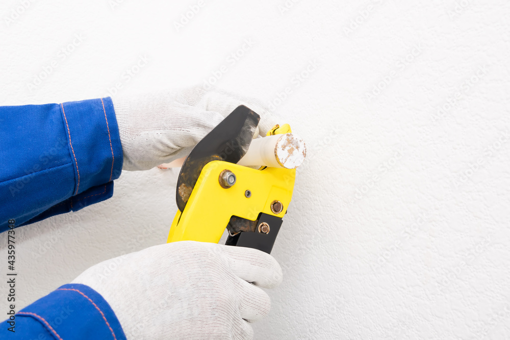 Obraz premium worker cuts off XLPE pipe for plumbing, close-up