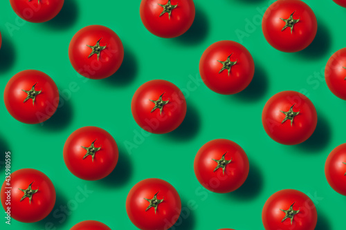 Pattern of fresh and ripe tomatoes isolated on a vibrant green background. Creative minimal food concept. Juicy and organic vegetables composition. Flat lay, top view. © Aleksandar