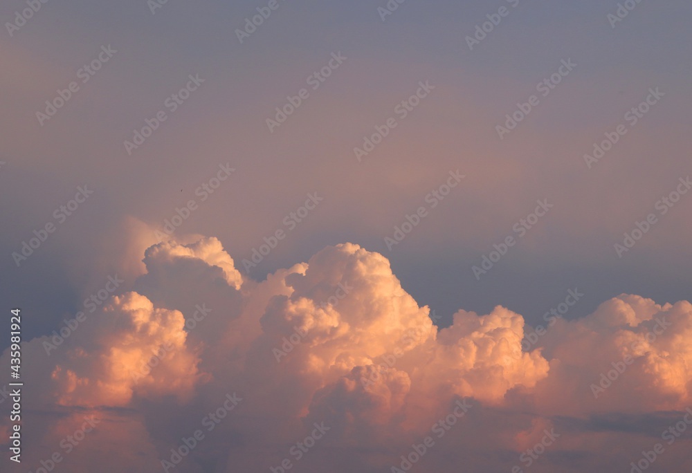 Bright colorful cumulus clouds on sunset sky. Background cloudscape wallpaper with copy space