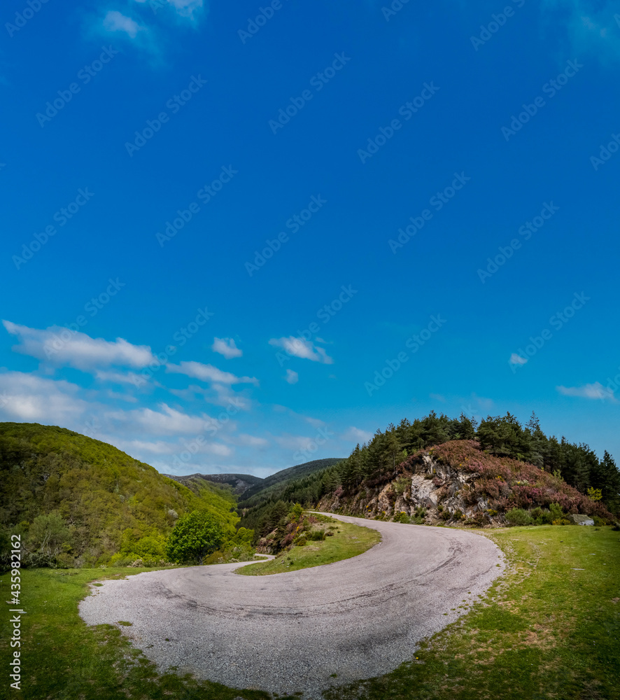 Steep high slope u-shape mountain road under blue sky