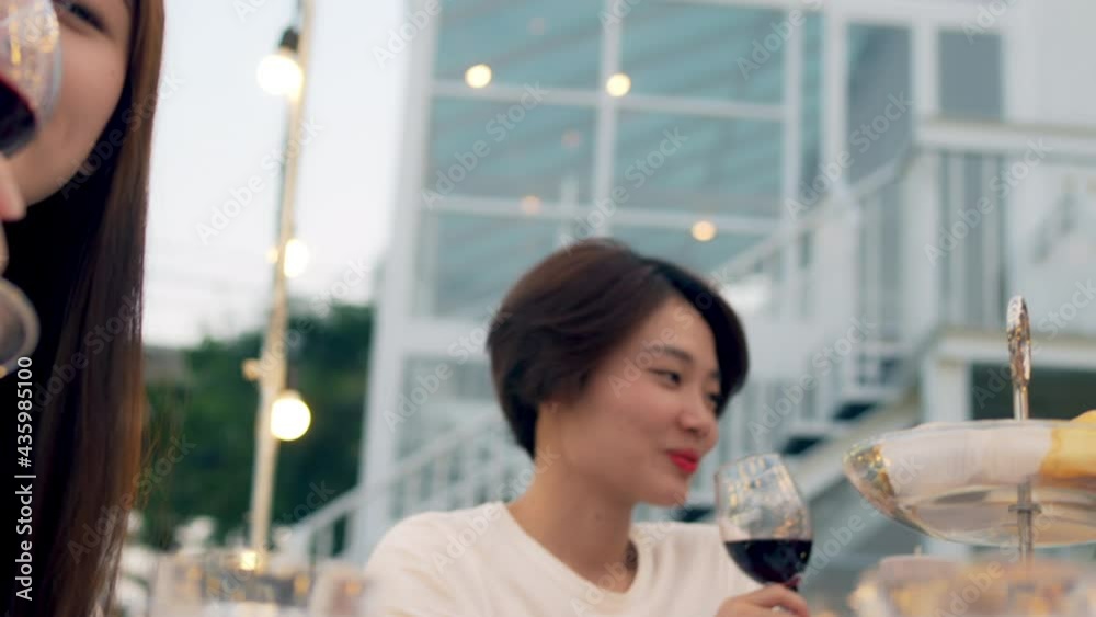 Asian woman have outdoor dinner party in the garden with friends at night. Happy female friendship raise wine glasses for celebration toast at dinner party nightlife with eating and drinking together. Asian woman have outdoor dinner party in the garden with friends at night. Happy female friendship raise wine glasses for celebration toast at dinner party nightlife with eating and drinking together.