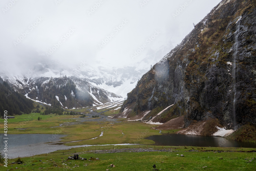 fog and rain on a cold spring day in the alps, the hohe tauern national park in austria, on a mountain lake
