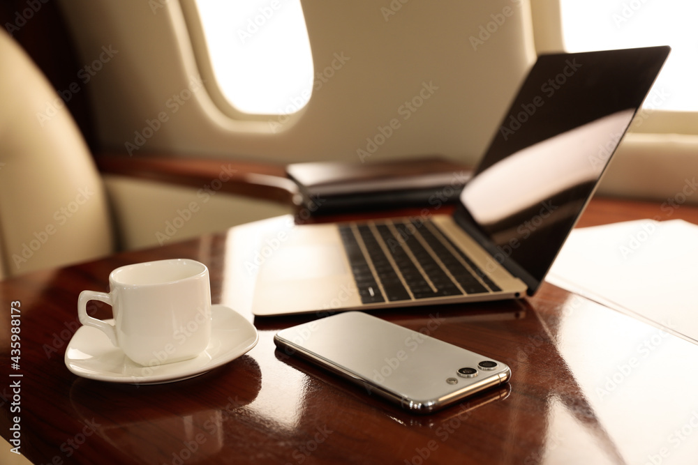 Cup of coffee with laptop and smartphone on table in airplane Cup of coffee with laptop and smartphone on table in airplane