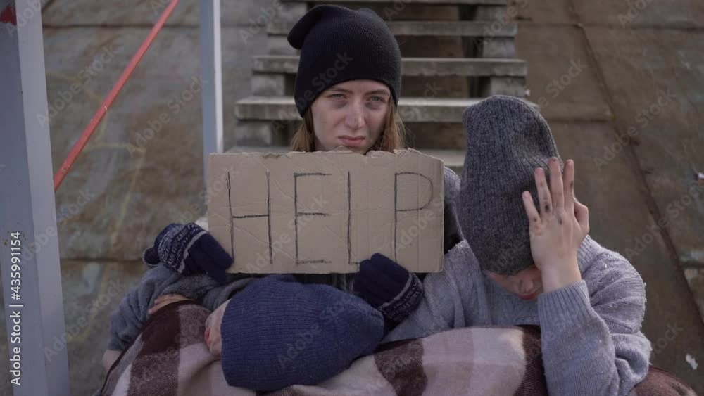 homeless mother with children with a sign Help on the stairs in an ...