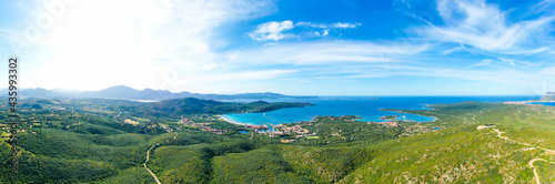 View from above, stunning aerial view of a mountain range covered by a green vegetation with a beautiful beach in the distance bathed by the mediterranean sea. Porto Rotondo, Sardinia, Italy. © Travel Wild
