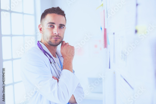 Young and confident male doctor portrait standing in medical office. photo