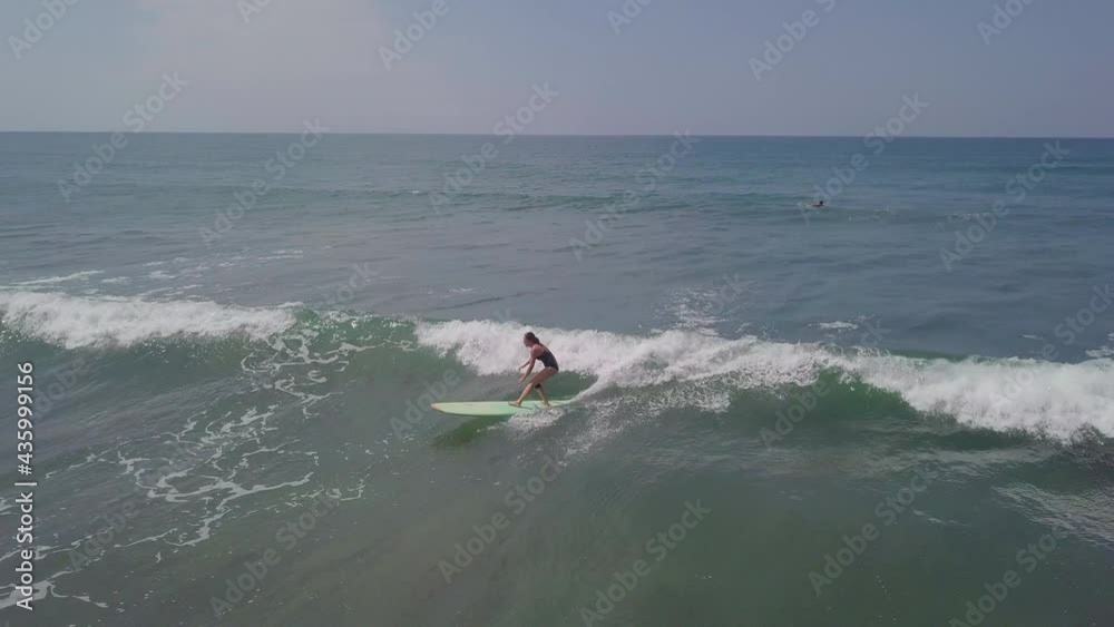 Aerial Shot Of Female Surfer Surfing On Sunny Day, Drone Flying Over Ocean During Vacation Against Clear Sky - Zambales, Philippines Aerial Shot Of Female Surfer Surfing On Sunny Day, Drone Flying Over Ocean During Vacation Against Clear Sky - Zambales, Philippines