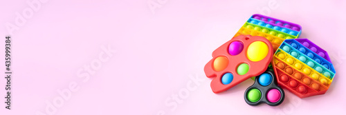Colorful anti-stress fidget push pop it sensory toys for children isolated on pink background. Simple dimple. Top view, flat lay. Selective focus. Banner