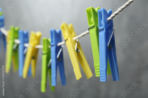 Green plastic clothespins on rope against grey background, closeup