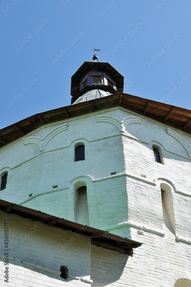 View of the white stone tower of the monastery. Tower with small windows against the sky, clear sunny day.