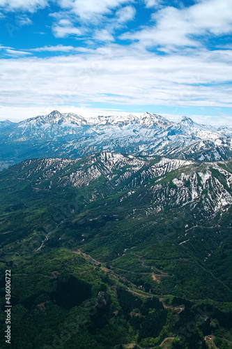 緑の山麓に残雪の山頂が雄大な春の山地 © BEIZ images