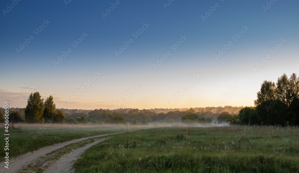 Sunrise over the meadow in the morning fog. Morning sunrise. Deruvia in dense fog. Natural landscape. Weather. Early morning