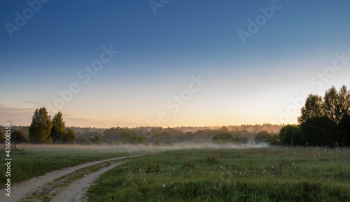 Sunrise over the meadow in the morning fog. Morning sunrise. Deruvia in dense fog. Natural landscape. Weather. Early morning © Sergei