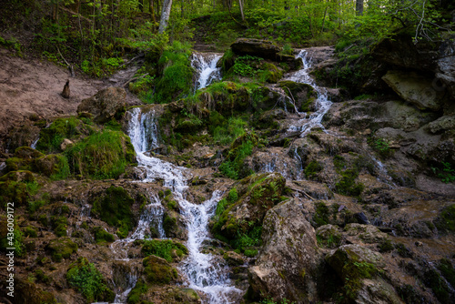 Beautiful mountain rainforest waterfall with fast flowing water and rocks, long exposure. Natural seasonal travel outdoor background with sun shihing photo