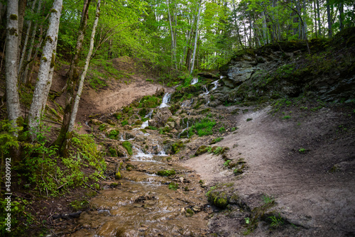 Beautiful mountain rainforest waterfall with fast flowing water and rocks, long exposure. Natural seasonal travel outdoor background with sun shihing photo