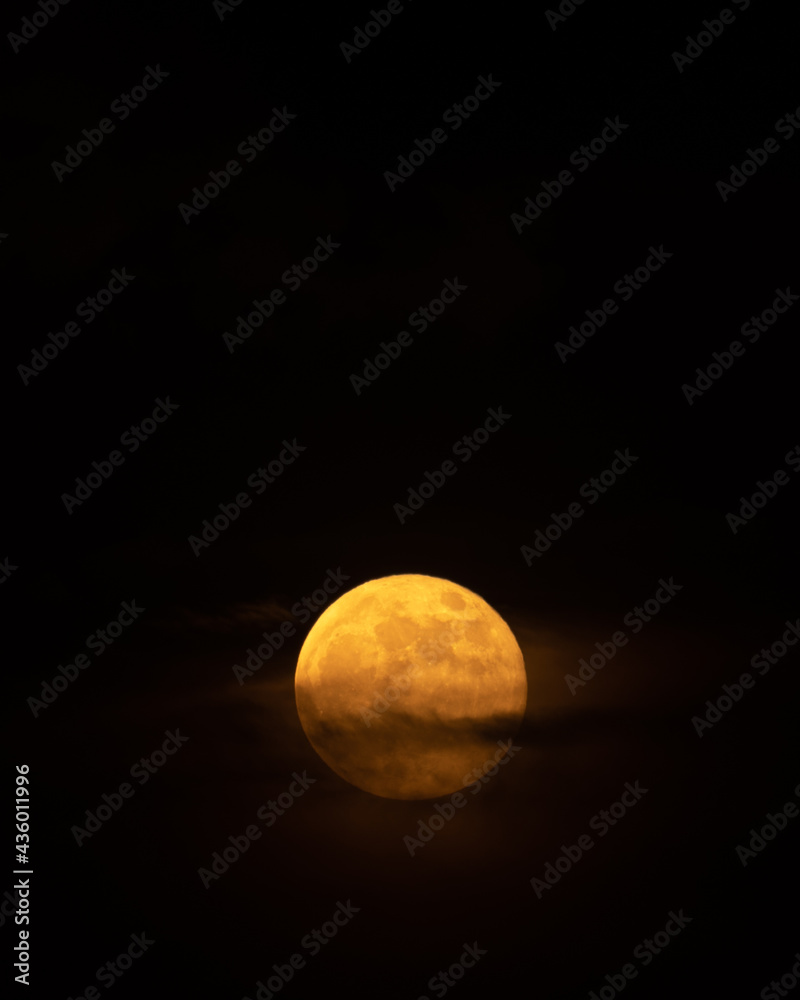 Yellow New Moon rises behind the clouds. Blood moon. Flower moon. Lunar eclipse. Astronomy and astronomical concept. Yellow New Moon rises behind the clouds. Blood moon. Flower moon. Lunar eclipse. Astronomy and astronomical concept.