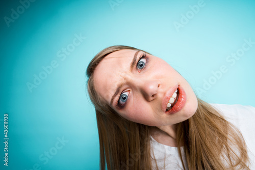 Close-up photo, fish eye. The girl is surprised and opening her mouth tilts her head to the side looking at the camera