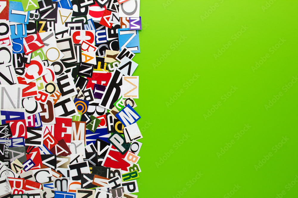 Fototapeta premium Alphabet letters cutting from paper magazine on green background with copy space for text. Abstract collage from clippings with newspaper magazine letters.
