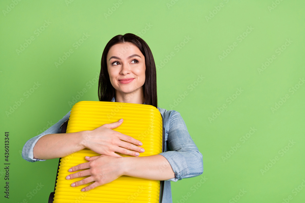 Photo of young dreamy smiling pretty girl look copyspace hug embrace luggage isolated on green color background Photo of young dreamy smiling pretty girl look copyspace hug embrace luggage isolated on green color background
