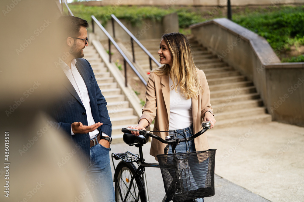 Obraz premium Young businesswoman standing on the street with bicycle. Beautiful businesswoman talking with her colleague