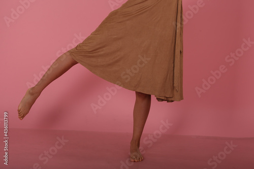 Beautiful female legs and brown dress on pink background