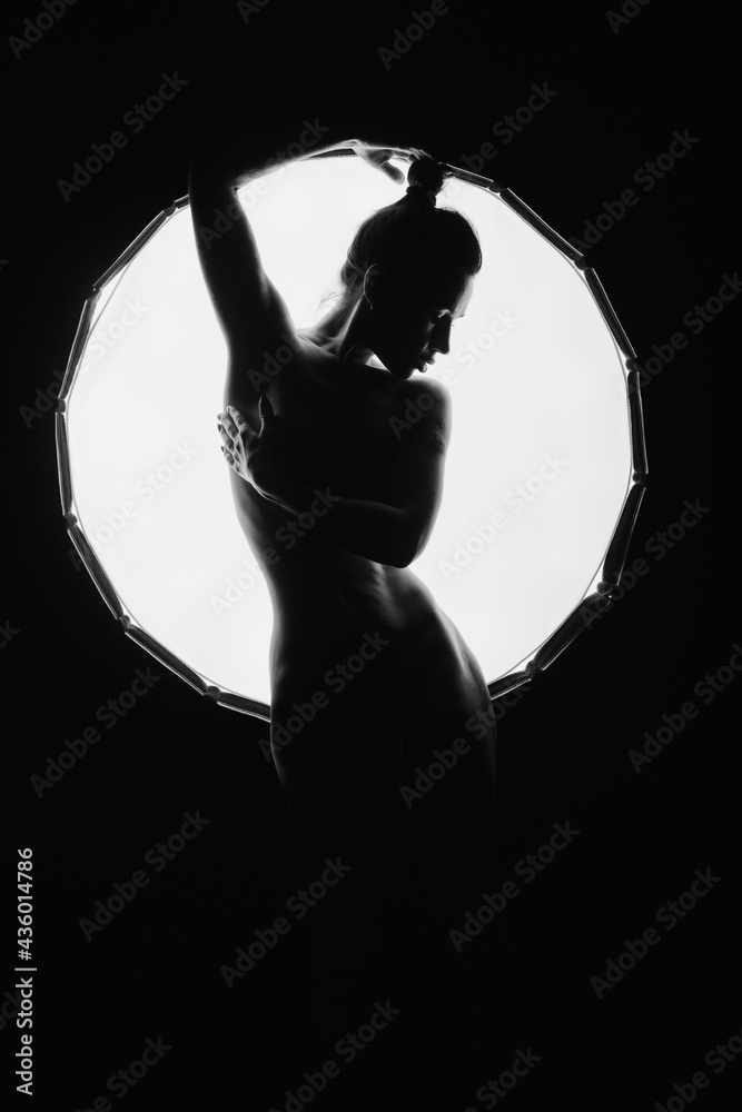 The silhouette of a young, slender, in the light of softbox.