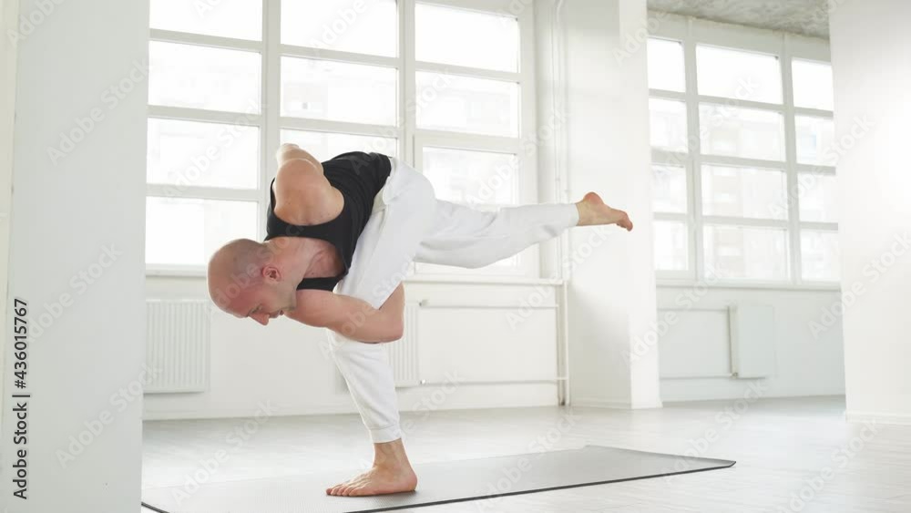 Calm caucasian yogi male with bald head keep balance while performing posture on one leg, standing on fitness mat. Calm caucasian yogi male with bald head keep balance while performing posture on one leg, standing on fitness mat.