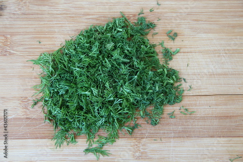 Chopped dill on the wooden cutting board, close-up