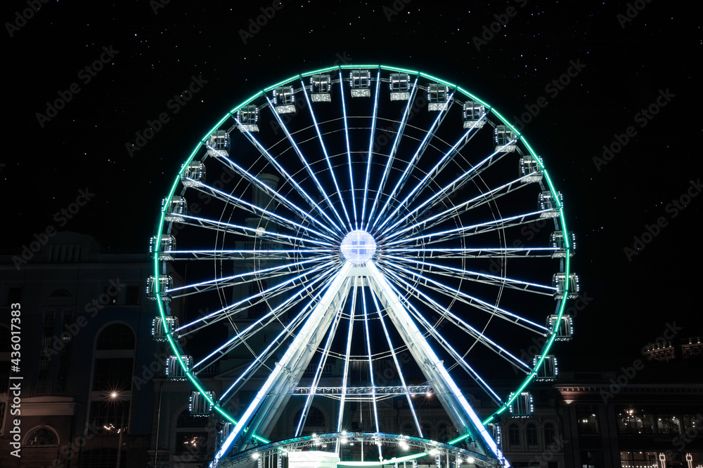 Beautiful glowing Ferris wheel on city street at night