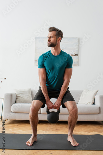 barefoot sportsman training with kettlebell at home