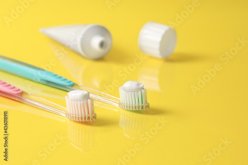 Brushes with toothpaste and tube on yellow background