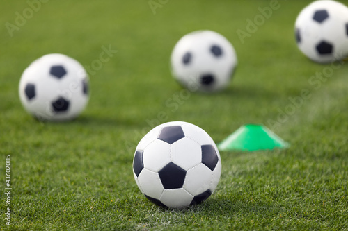 Training Classic Soccer Football Balls on Grass Field. White and Black Soccer Balls and Training Cone Marker. Sports Ball on Pitch Sideline